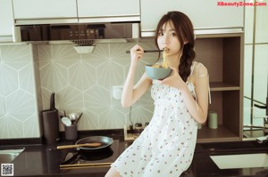 A woman sitting on the floor eating a bowl of food.