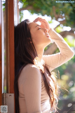 A woman in a purple lingerie standing in front of a window.