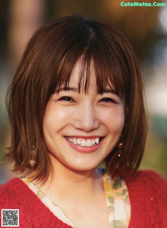 A woman in a red sweater smiles at the camera.