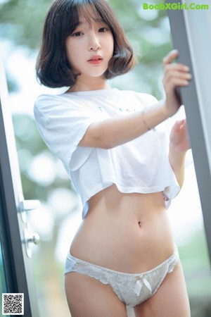 A woman in a white shirt and white shorts crouching on the ground.