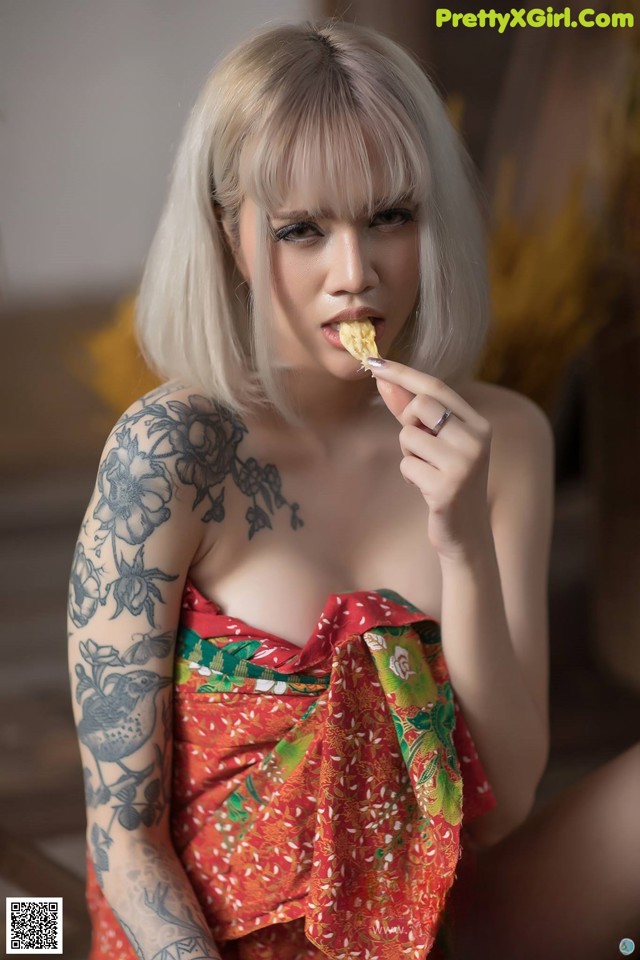 A woman in a red dress eating a piece of food.