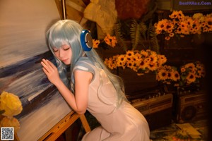 A woman with blue hair sitting on the floor holding a sunflower.