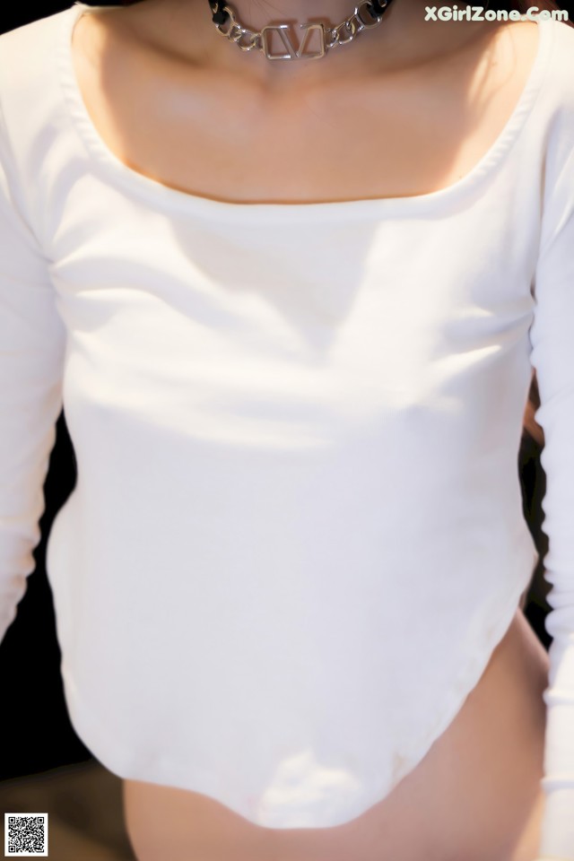 A woman wearing a white shirt and a necklace.