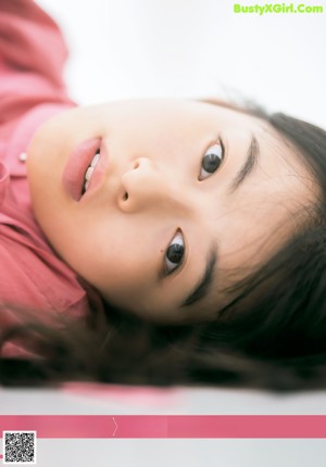 A woman leaning against a wall with her hands on her head.