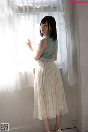 A woman in a white dress is posing for the camera.