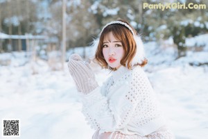 A woman in a white dress and a red hat in the snow.