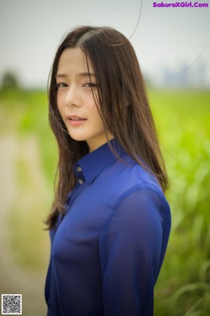 A woman in a white shirt and blue skirt standing in a field.