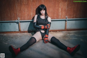 A woman in a black top and skirt crouching on the ground.