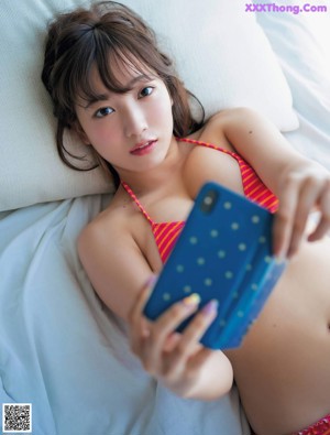 A woman in a purple bikini sitting on a bed with a teddy bear.