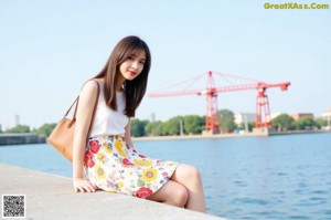 A woman in a white top and floral skirt posing for a picture.