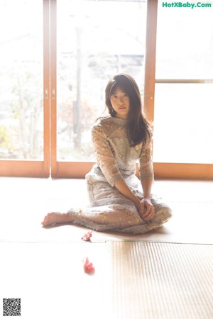 A woman laying on the floor with a flower in her hand.