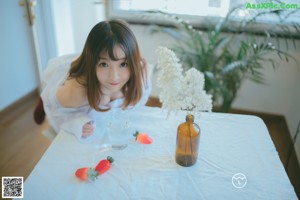 A woman in a white shirt and red stockings sitting on the floor.