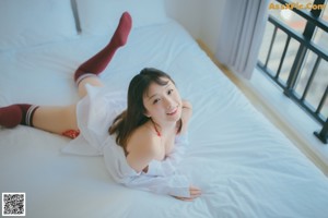 A woman in a red and white lingerie standing on a bed.