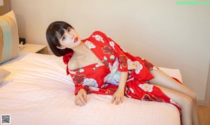 A woman in a red kimono sitting on a table.