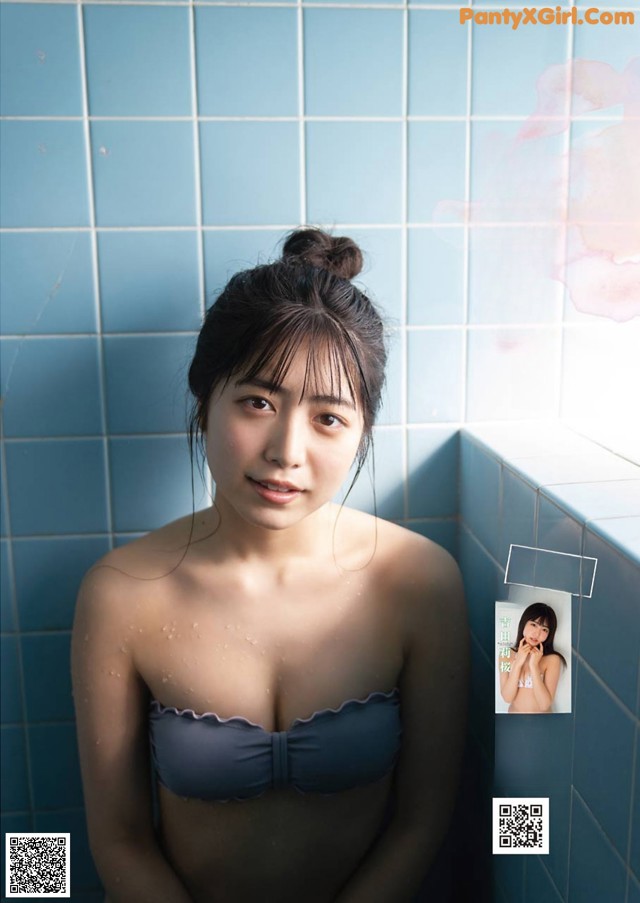 A woman in a blue bikini sitting in a bathtub.