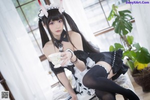 A woman dressed as a maid sitting on a table.