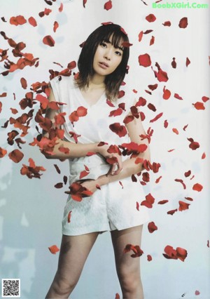 A woman holding a red rose in front of her face.