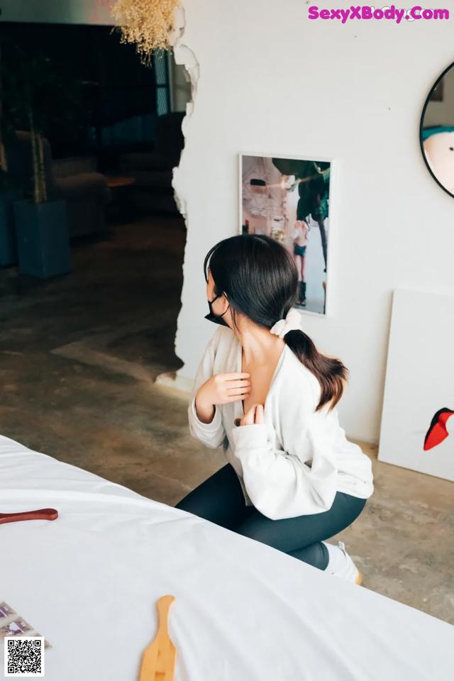 A woman sitting on top of a bed next to a mirror.