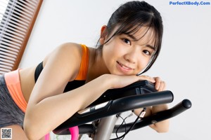 A woman sitting on a stationary bike in a gym.