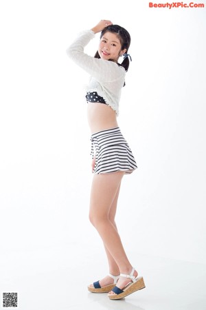 A woman in a white top and black and white striped shorts.