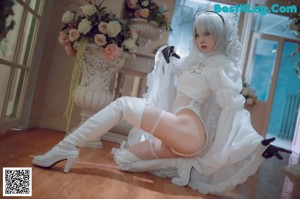 A woman in a white dress and thigh high boots posing for a picture.