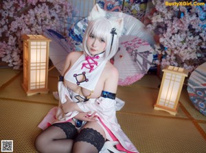 A woman in a kimono sitting on the floor with an umbrella.