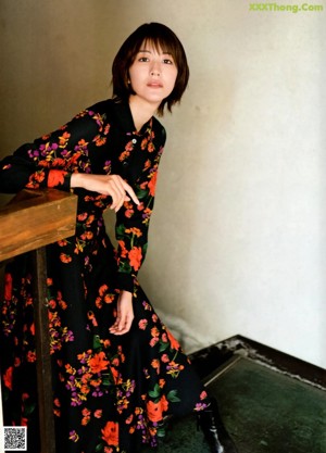 A woman in a floral dress is walking on a rooftop.