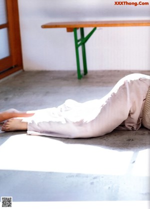 A woman laying on the floor in a white sweater.