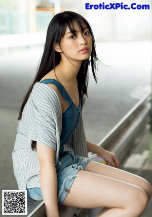 A woman in a bikini leaning against a wall.