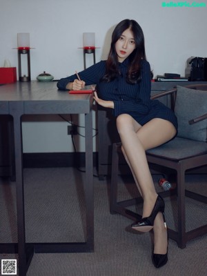 A woman sitting at a desk with her legs crossed.