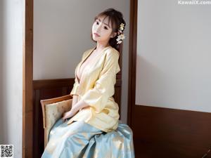 A woman in a blue shirt and skirt sitting on a window sill.