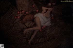 A naked woman holding an apple in front of her face.