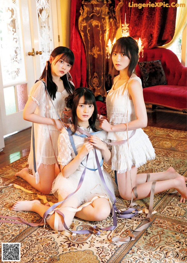 A group of three young women sitting on a rug.