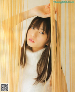 A woman leaning against a wooden wall with her hand on her chin.