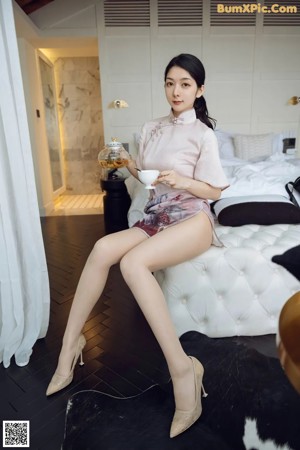 A woman sitting on top of a white bed.