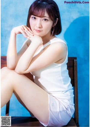 A woman in a white dress sitting on a chair.