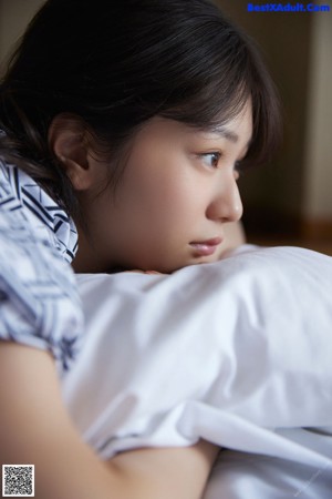 A woman in a kimono sitting on a bed.