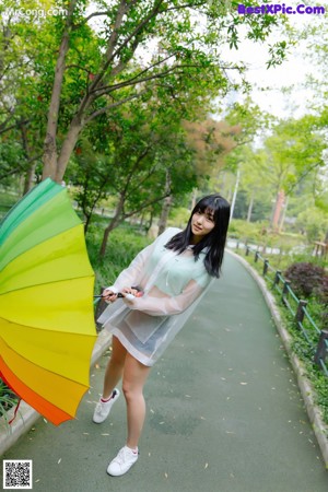 A woman leaning against a fence with an umbrella.