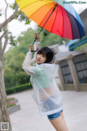 A woman in a white shirt and black shorts holding an umbrella.