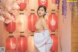 A naked woman in a kimono posing in front of a tree.