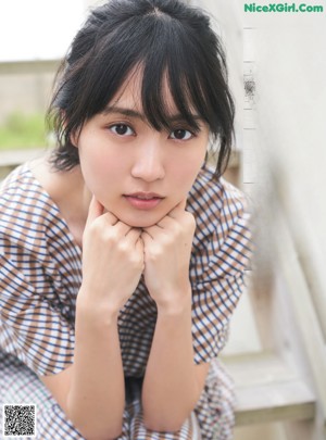 A woman with long black hair wearing a blue shirt.