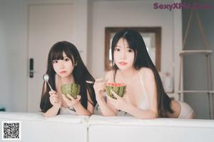 A couple of women sitting on top of a white couch.