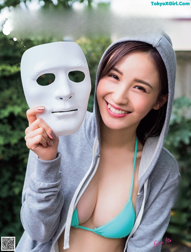 A woman in a blue bikini holding a white mask.